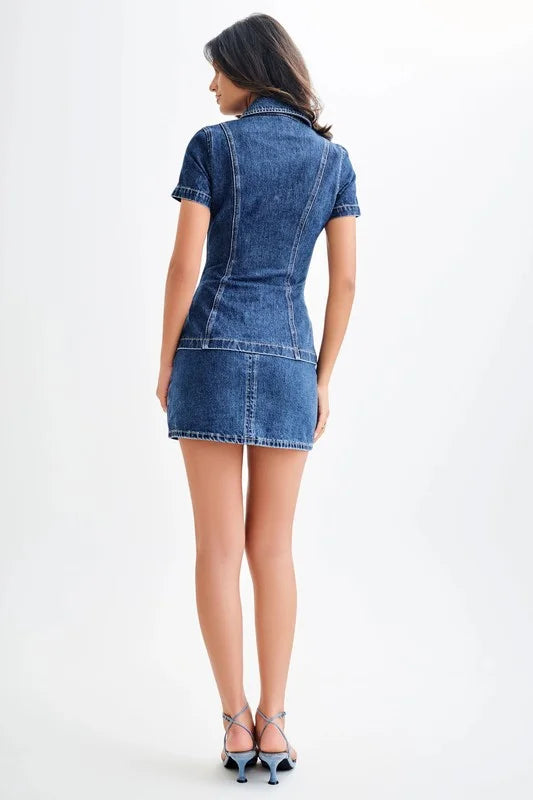 Back view of a women's blue denim two-piece set featuring a short-sleeve top and mini skirt, paired with light blue strappy heels, showcasing a trendy 2025 fashion look